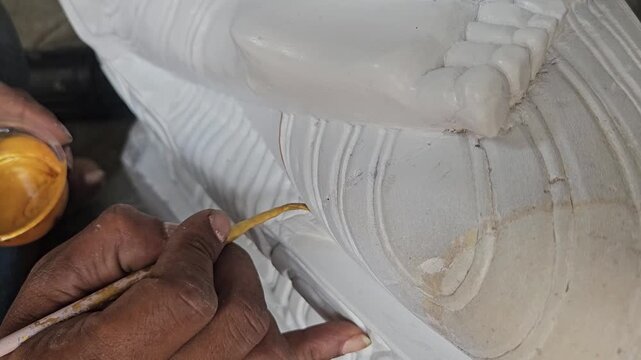 Hand of an artist doing paint on statue