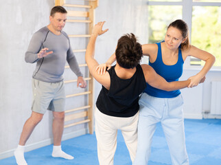 Young man and woman in sparring improve skill of performing strangulation and neutralizing enemy. Training in martial art of krav maga