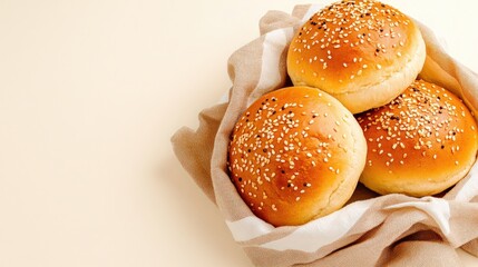 Burger buns, sprinkled with sesame seeds, in soft, light cloth on white background, copy space