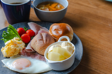 Western style breakfast with bread, fried egg, ham, salad, banana, and coffee
