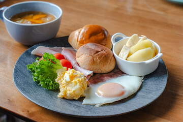 Western style breakfast with bread, fried egg, ham, salad, banana, and coffee
