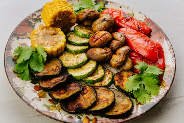 Grilled vegetables with herbs on ceramic plate. Colorful healthy vegan meal top view