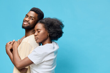 Couple embracing on blue background, expressing joy and love with natural hairstyles and casual...