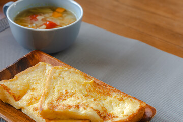 French toast breakfast with soup on wooden plate
