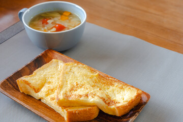 French toast breakfast with soup on wooden plate
