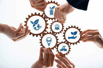 Hands are working together to turn gears featuring green icons, symbolizing innovation and sustainability in business practices aimed at protecting the environment. Amity