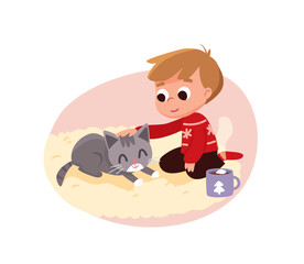 A little boy wearing a Christmas sweater sitting on the floor, rug petting his kitten. Cup of hot chocolate with marshmallows  beside him, nearby.