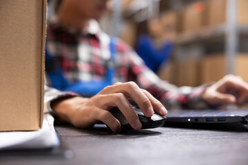 Asian employees working in warehouse with packed goods on racks, in house product handling and...