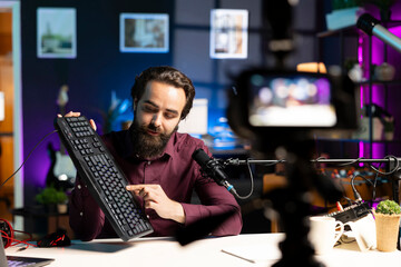 Influencer filming keyboard review in apartment, showing typing capabilities. Technology guru...