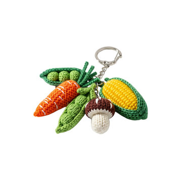A colorful keychain featuring crocheted vegetables including a carrot, corn, peas, and a mushroom. The background is transparent, highlighting the keychain's details.