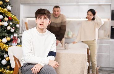 Obraz premium Domestic quarrel during Christmas celebration - father and sister scolding young guy in home kitchen