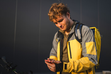 Deliveryman using smart phone next to his bike