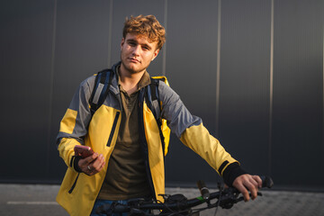 Delivery man using smart phone and holding his bicycle