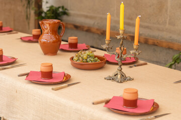 Medieval table setting featuring clay dishes, candlestick, and grapes