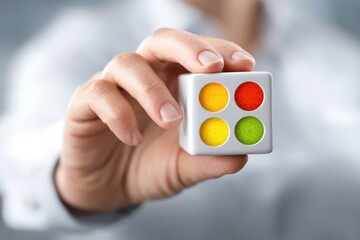 Person's hand holds a cube with colored indicators for status and risk