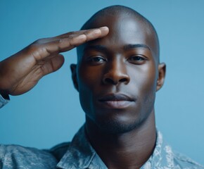 Close-up portrait of a man in military uniform saluting against a vivid light-blue backdrop, showcasing a serious and respectful expression.