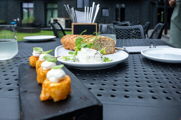 Freshly prepared colorful appetizers served on a black wooden platter alongside creamy cheese and artisan bread, creating a vibrant and healthy dining experience with copy space