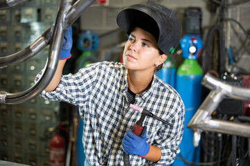 Young female metallurgist working with welding machine in metallurgical workshop