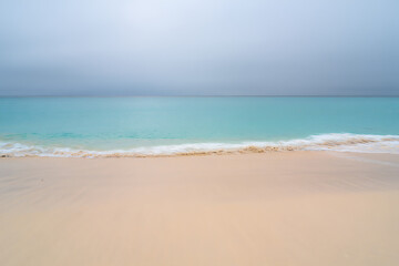 A serene tropical beach in Thailand with white sand and turquoise water under a blue sky