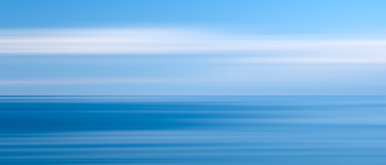 sky is a beautiful shade of blue with  few fluffy clouds scattered throughout.  ocean is calm and peaceful, with no signs of waves or turbulence.  scene is serene and tranquil