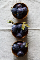 Ripe purple plums in a plate on a table top view indoors