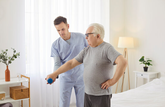 Elderly man performs dumbbell exercises with the support of a doctor or caregiver, emphasizing the role of healthcare in rehabilitation and physiotherapy. A structured recovery session unfolds.