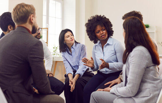 Group of business people in office sitting in circle listening to african american woman, close-up. Concerned boss talking to team. Concept upset colleague, active listening skills