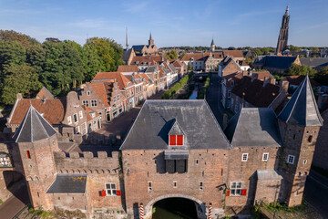 Aerial view double gated medieval city entrance Koppelpoort structure in Amersfoort, The Netherlands, with the authentic rooftops of the historic center in the background