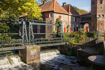 Dam sluice gate and waterworks outside historic double gated access medieval city entrance Koppelpoort structure in Amersfoort, The Netherlands, in the Rijn canal water in the foreground 