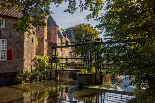 Dam sluice gate and waterworks outside historic double gated access medieval city entrance Koppelpoort structure in Amersfoort, The Netherlands, in the Rijn canal water in the foreground 