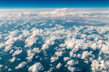  Fluffy white cumulus clouds cover the landscape with a deep blue sky above
