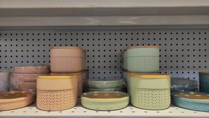 Neatly arranged pastel storage containers with wooden lids displayed on a supermarket shelf, highlighting modern and practical home organization design