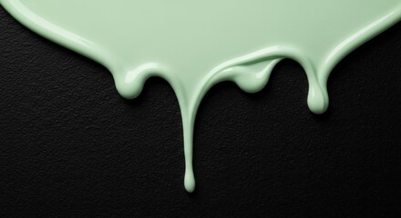 Dripping mint green paint on a textured black surface, creating an artistic contrast and depth
