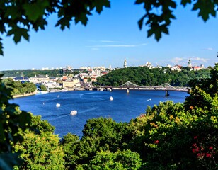 Panoramic view of a city by a river, framed by foliage