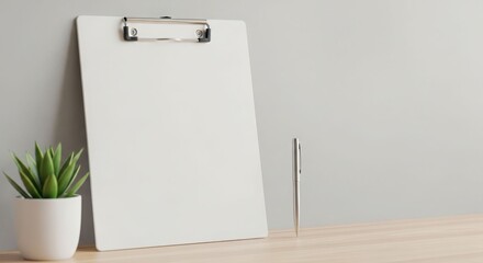 A blank clipboard leans against a wall next to a small potted succulent and a pen.