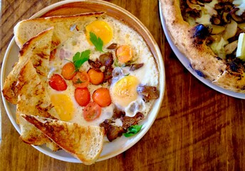 A beautifully plated brunch with sunny-side-up eggs, cherry tomatoes, toast, and sautéed mushrooms, full of color and flavor