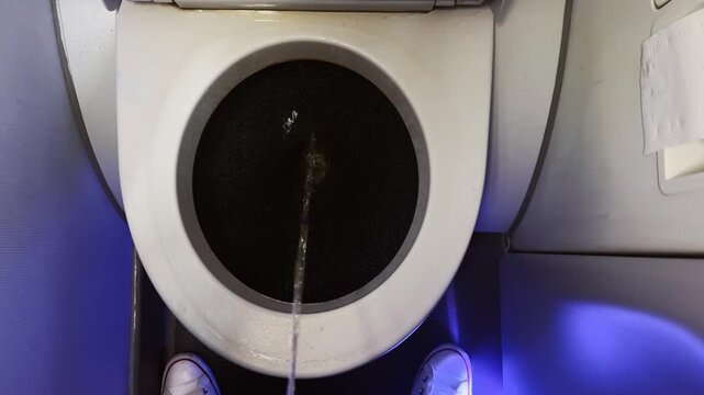 Top view pov man urinate in airplane lavatory toilet during flight