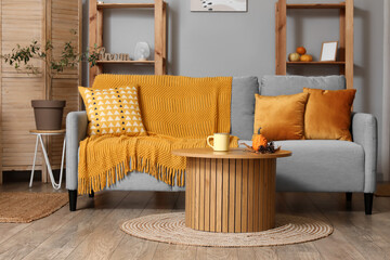 Interior of modern living room with grey sofa and pumpkins on coffee table
