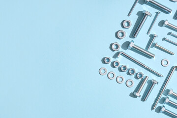 Arrangement of different tap bolts, chrome nuts and hex keys on blue background