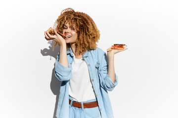 Cheerful young woman with curly hair enjoying healthy snacks, showcasing vibrant personality against a bright minimalist background