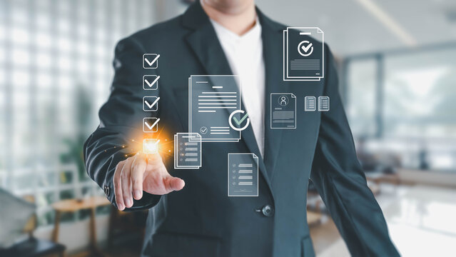 A businessman in a suit touches a glowing digital checkbox on a virtual interface. This represents completing tasks, approving documents, or quality control in a modern office environment.