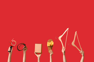 Female hands with wardrobe box, accessories and adhesive tape on red background