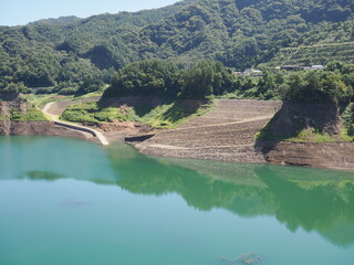 Gunma, Japan - September 7, 2025: Appeared due to drought, submerged disused railroad tracks, roads, basements and trees under the water of Yamba Dam in Gunma, Japan