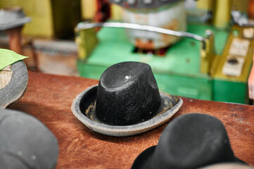 Felt hat die resting on a workbench surrounded by tools and vibrant machinery in a bustling workshop setting
