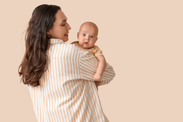 Beautiful young happy mother with her cute little baby on beige background