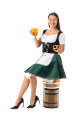 Young happy woman in traditional German clothes with glass of beer and pretzel sitting on barrel against white background