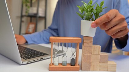 Working on a laptop while building a staircase of blocks to support a plant highlights upward growth, strategic planning, resilience, learning, and the nurturing of both career and personal ambitions.