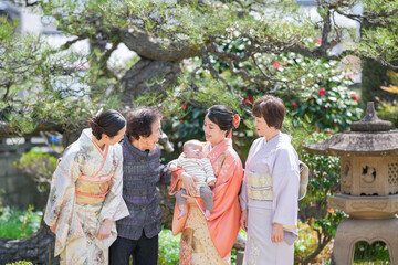 A group of women in traditional Japanese clothing are standing together, one of them holding a baby. Scene is warm and welcoming, as the women are embracing and showing affection towards each other