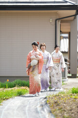 Fototapeta premium Three women in traditional Japanese clothing walk down a path. One of the women is holding a baby