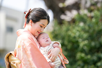 Obraz premium A woman is holding a baby in her arms. The baby is sleeping and the woman is smiling. Concept of warmth and love between the mother and child